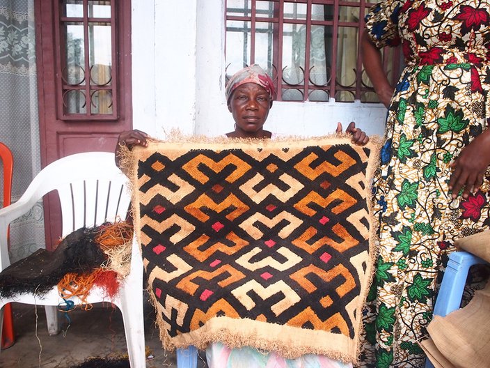 Maman Albérique LUKANU, with her Kuba x Mandombe rug. This piece took approximately three weeks to make by hand. Jess Kilubu